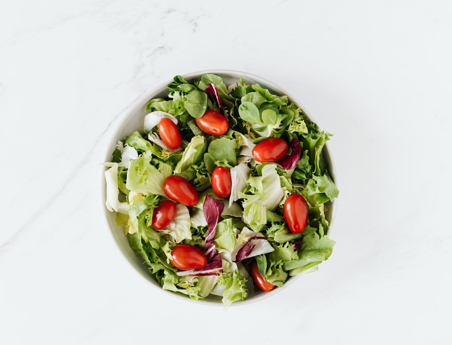 Fresh green salad with cherry tomatoes in a ceramic bowl