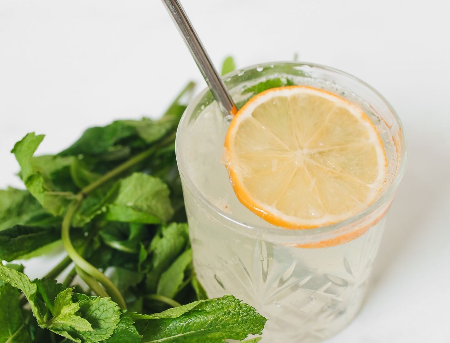 Lemon and mint water in a glass with a reusable metal straw