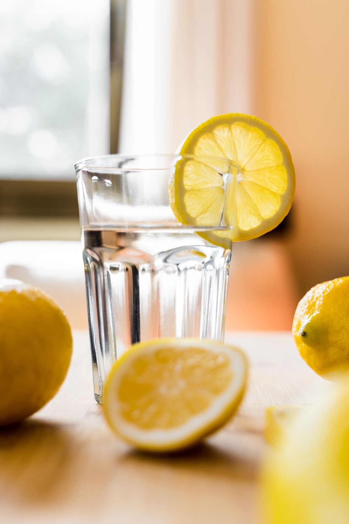 A glass of water with fresh lemons on a kitchen table